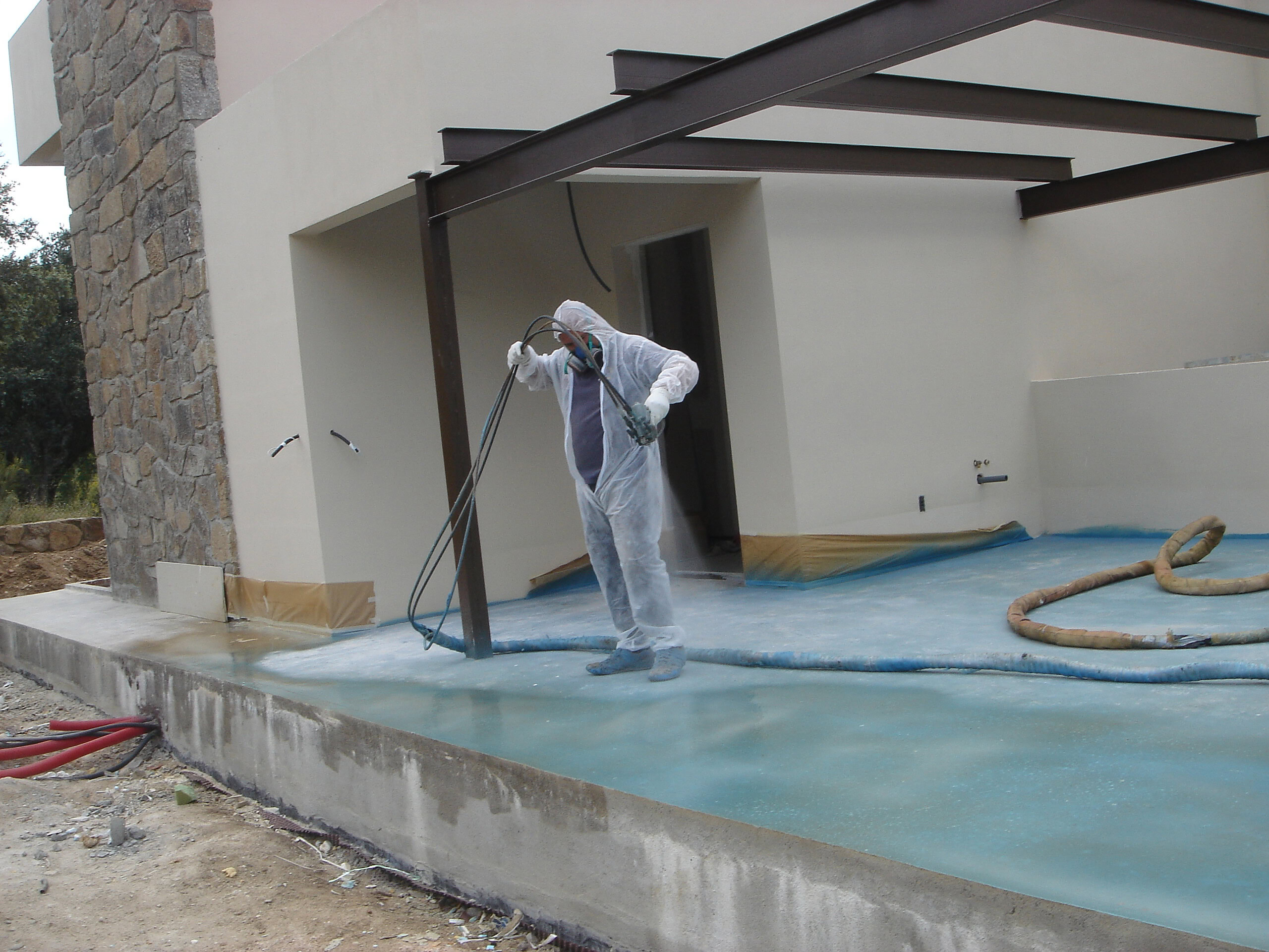 Trabajador aplicando impermeabilizante en construcción residencial.